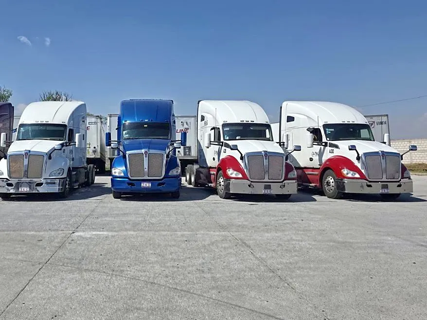 Cuatro tractocamiones de T&L LogistIQ formados de frente en el patio.