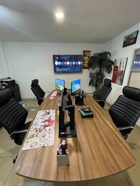 Sala de juntas con mesa para ocho personas y pantalla de presentaciones.