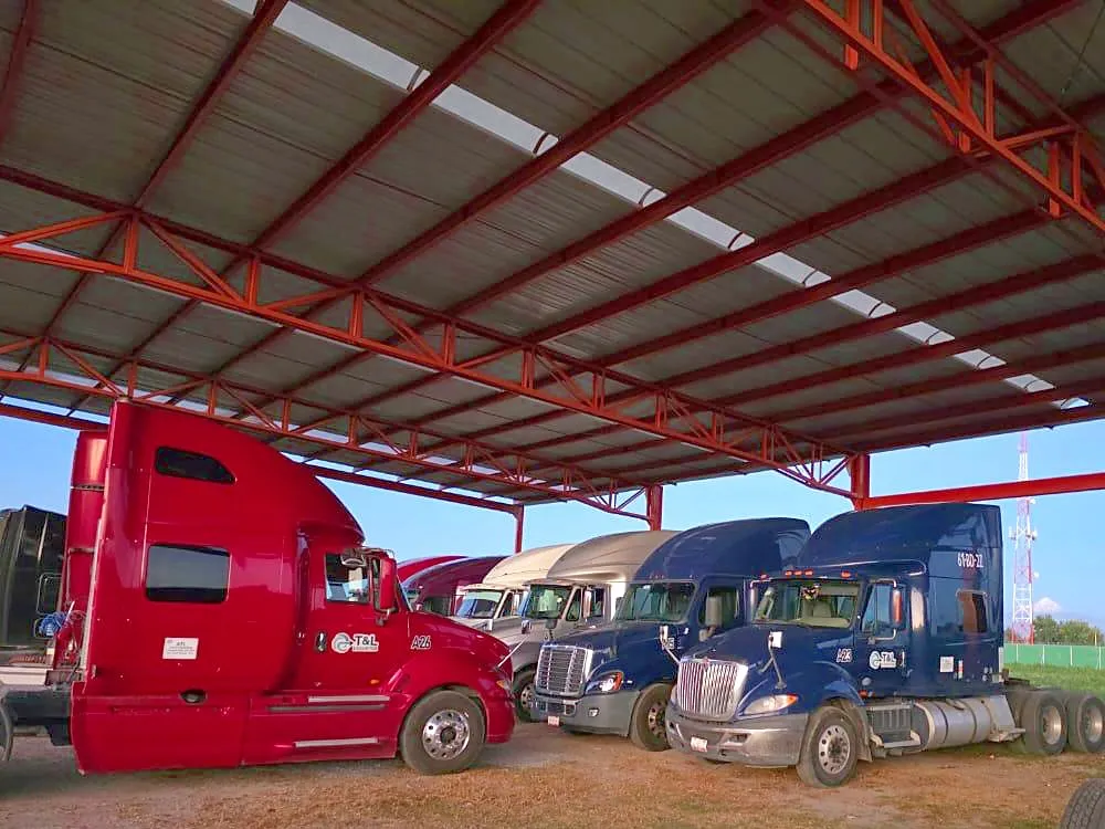 Tractocamiones de T&L LogistIQ formados bajo el techo del patio de la empresa.